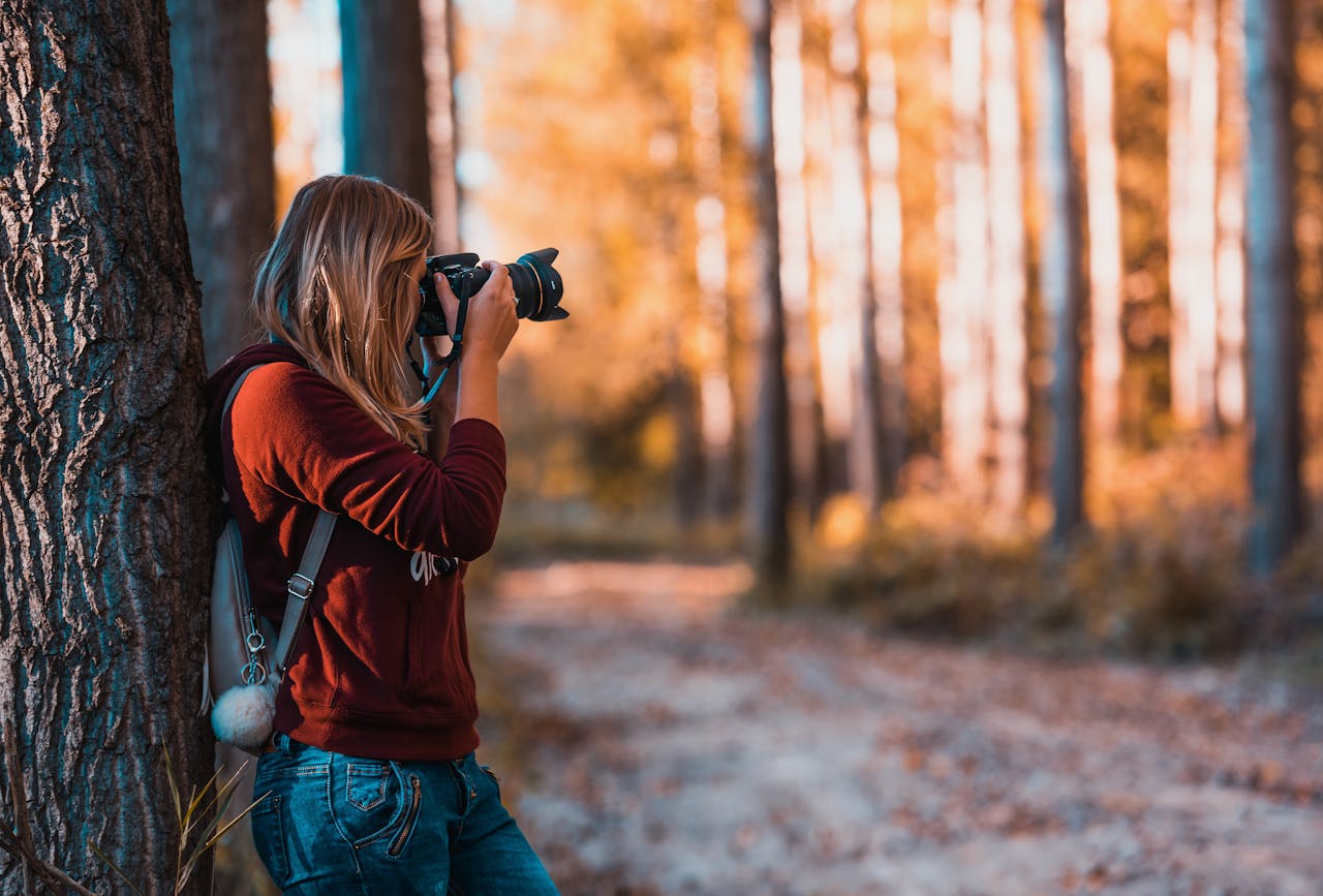 services-02 A woman taking photos in an autumn forest, perfectly capturing the beauty of nature.