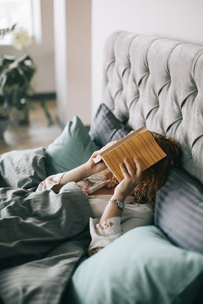 services-04 Woman resting in bed holding a book, creating a serene indoor atmosphere perfect for relaxation and leisure.